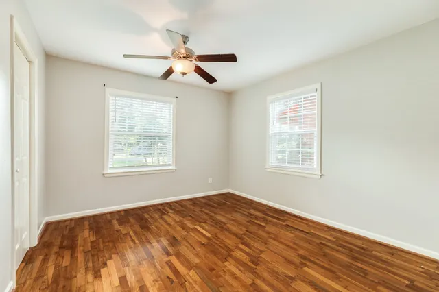 a view of empty room with wooden floor and fan