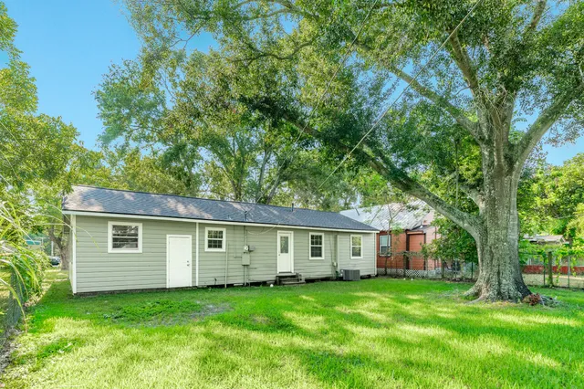 a view of a yard in front of a house with large trees