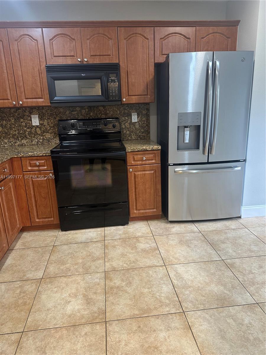 9724 Southwest 142nd Place Miami, FL 33186 - Photo 5 of 36 a kitchen with granite countertop a refrigerator and a stove top oven
