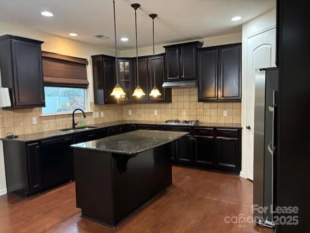 a kitchen with stainless steel appliances granite countertop a sink a stove and a refrigerator