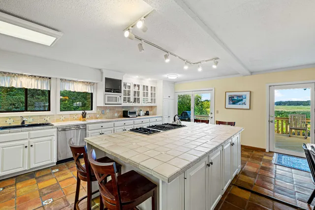 a kitchen with a stove a sink dishwasher and white cabinets with wooden floor