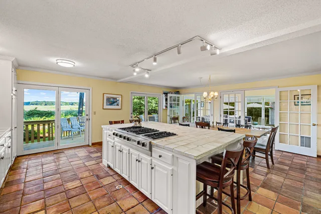 a kitchen with stainless steel appliances granite countertop a stove a refrigerator a dining table and chairs with the wooden floor