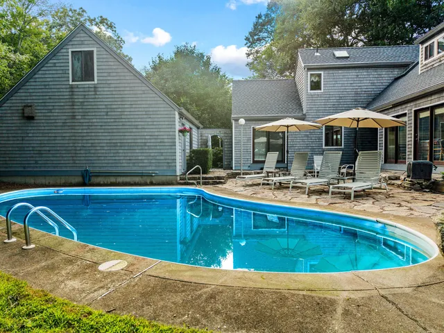 a view of a house with pool and chairs