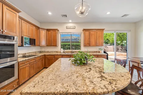 a kitchen with stainless steel appliances granite countertop a refrigerator a stove and a sink with wooden floor