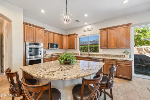 a kitchen with granite countertop kitchen island stainless steel appliances a stove a sink a table and chairs