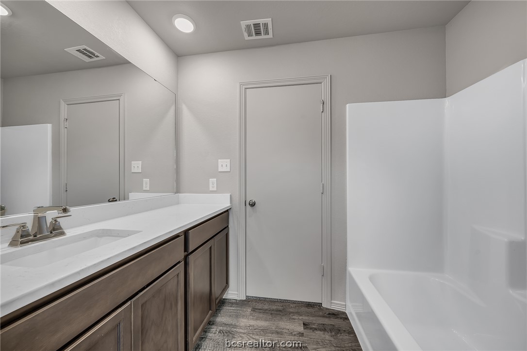 1635 Lucky Street Bryan, TX 77803 - Photo 10 of 11 a bathroom with a granite countertop sink a mirror and a bathtub