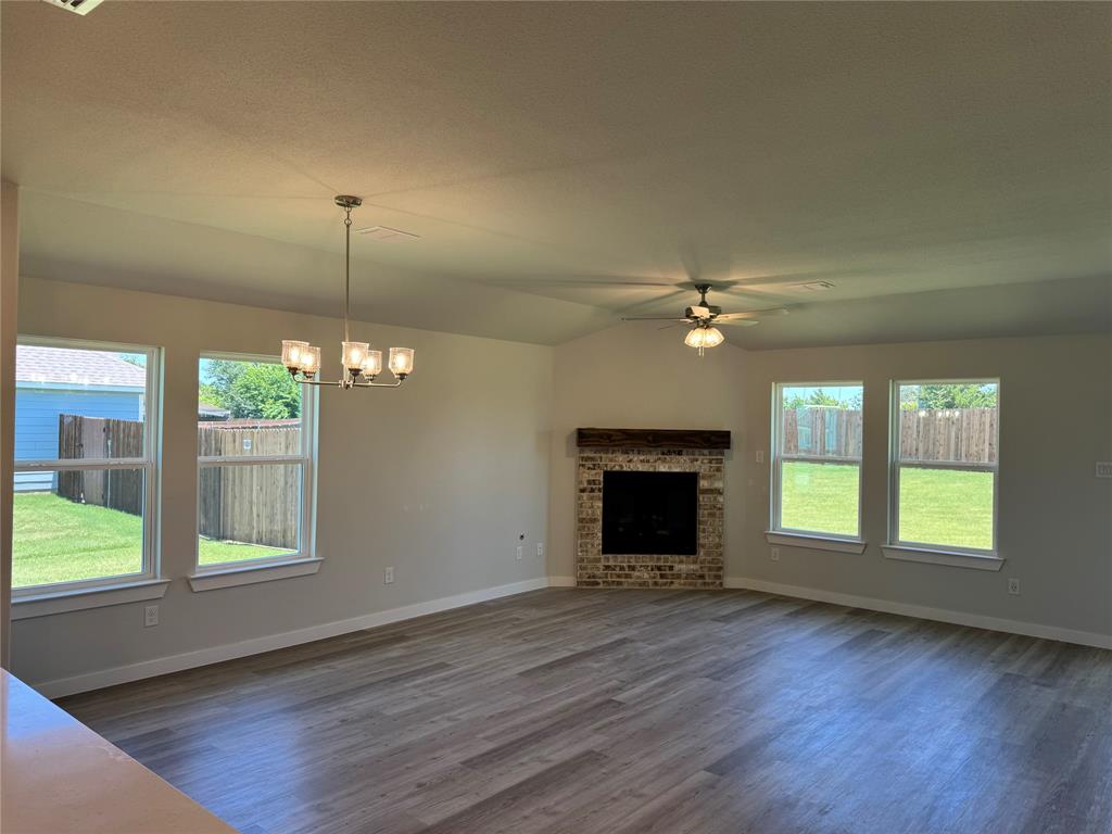 605 Finlee Way Tioga, TX 76271 - Photo 9 of 22 an empty room with windows fireplace and wooden floor