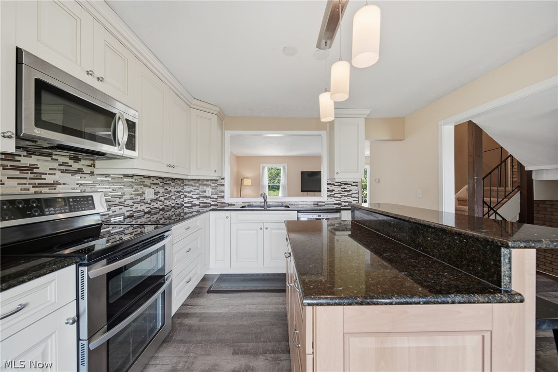824 South Chillicothe Road, Unit 2 Aurora, OH 44202 - Photo 4 of 42 Kitchen featuring dark granite countertops, white cabinetry, stainless steel appliances, wood-finish flooring, and a mosaic tile backsplash