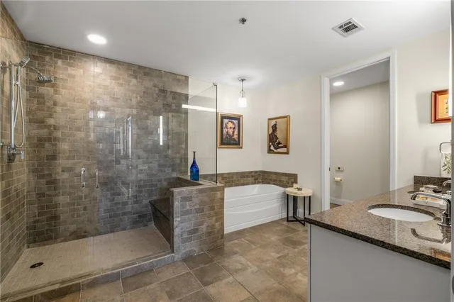 a bathroom with a granite countertop sink a mirror a bathtub and shower