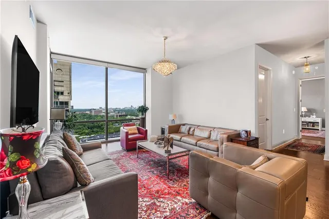 a living room with furniture a flat screen tv and a floor to ceiling window