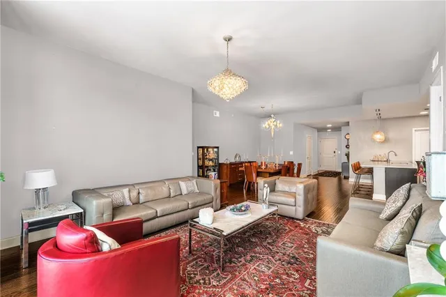 a living room with furniture kitchen view and a chandelier