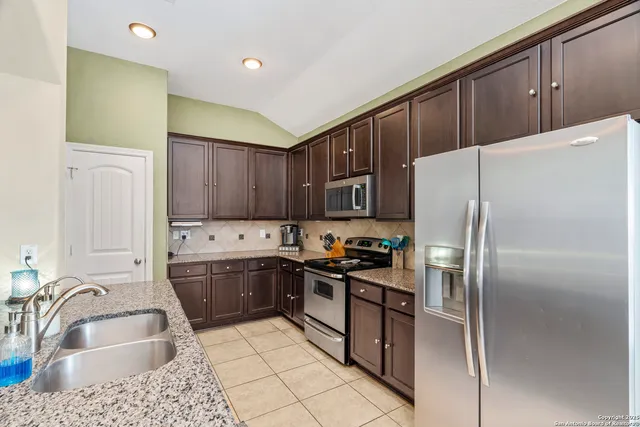 a kitchen with stainless steel appliances granite countertop a refrigerator sink and stove