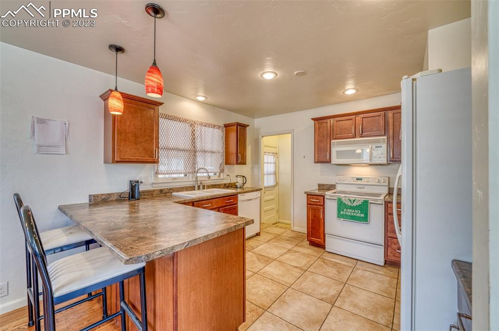 45 Duke Street Pueblo, CO 81005 - Photo 9 of 49 a kitchen with a sink a stove a refrigerator and chairs