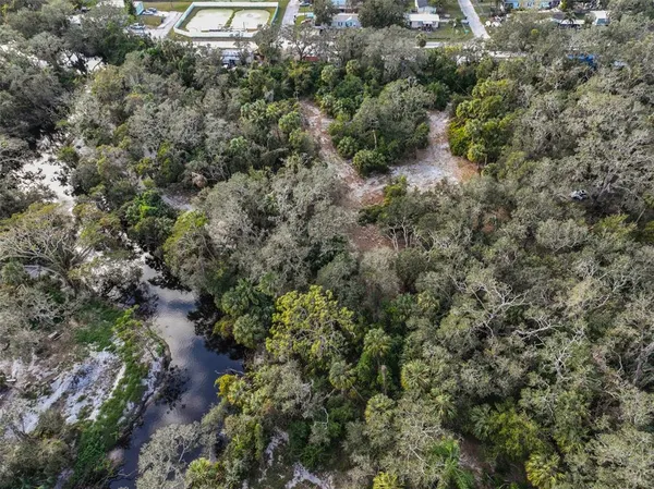 an aerial view of residential house with outdoor space and trees all around