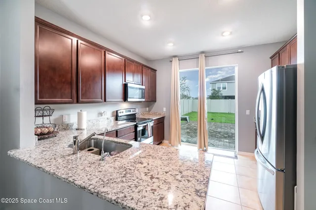a kitchen with stainless steel appliances granite countertop sink stove refrigerator and cabinets