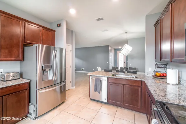 a kitchen with stainless steel appliances granite countertop a refrigerator a stove and a sink