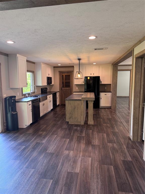 7268 Brangus Road Anna, TX 75409 - Photo 21 of 21 Open-concept kitchen featuring wood-finish flooring, white cabinetry, dark countertops, a central island with a pendant light, and recessed lighting