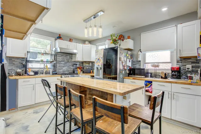a kitchen with stainless steel appliances kitchen island granite countertop a table chairs and a refrigerator