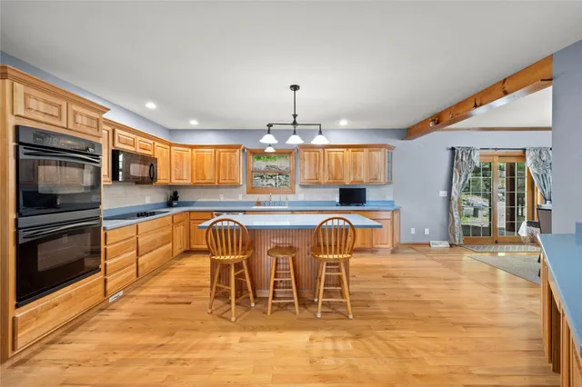 a kitchen with stainless steel appliances granite countertop a stove top oven a sink a dining table and chairs