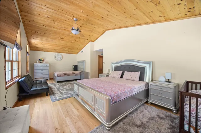 a spacious bedroom with a bed and wooden floor