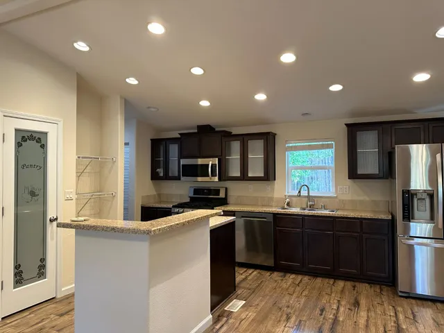 a kitchen with stainless steel appliances granite countertop a refrigerator a sink dishwasher a stove and a microwave oven on granite countertops