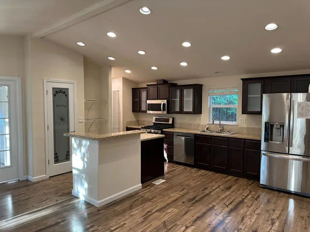 a kitchen with stainless steel appliances granite countertop a sink a stove a refrigerator and cabinets