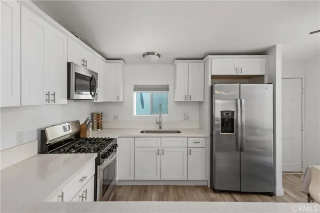 a kitchen with stainless steel appliances a refrigerator sink and white cabinets