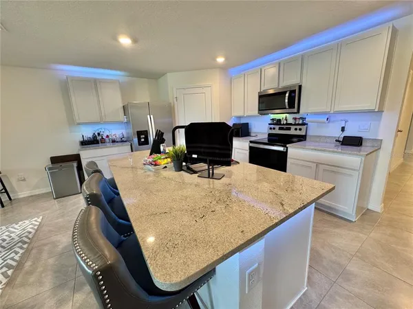 a kitchen with kitchen island granite countertop sink stove top oven and microwave