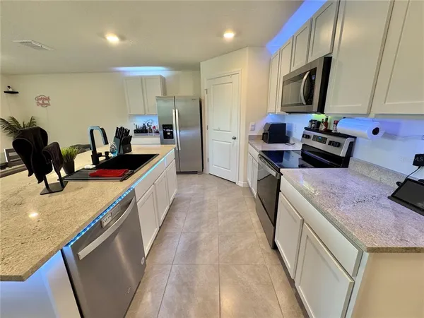 a kitchen with kitchen island granite countertop a sink a counter top space stainless steel appliances and cabinets