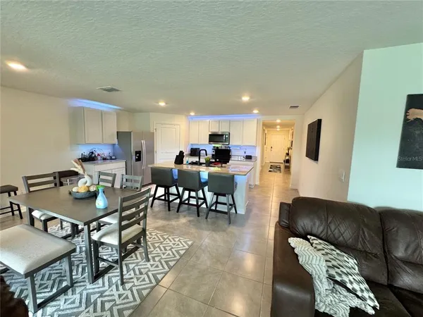 a living room with furniture and a dining table with kitchen view