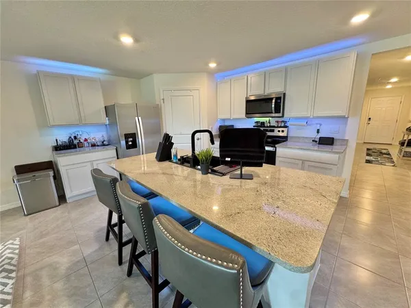 a kitchen with granite countertop a table chairs microwave and cabinets