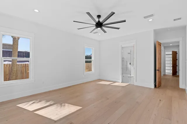 an empty room with windows and fan