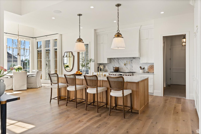 478 South Maple Lakes Drive Mapleton, UT 84664 - Photo 4 of 51 Spacious kitchen featuring a large wood-finish island with seating, white shaker cabinetry, marble backsplash, and dual pendant lighting