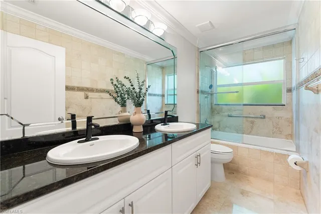 a bathroom with a double vanity sink toilet mirror and bathtub