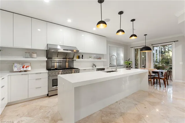 a large white kitchen with lots of counter space a sink and appliances