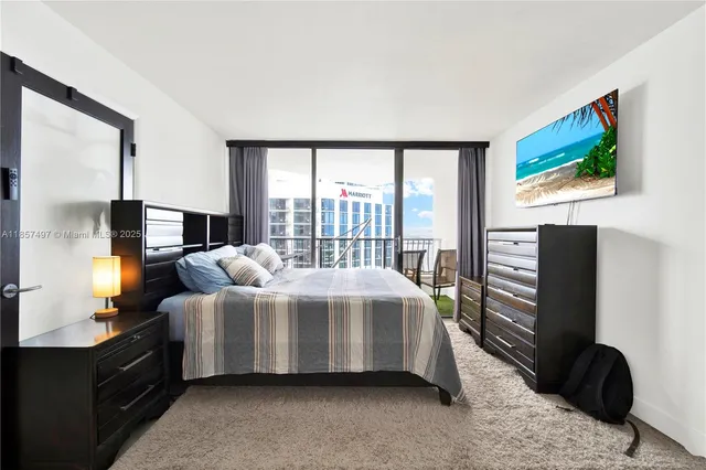 a bedroom with a bed television on desk and a window