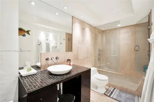 a bathroom with a granite countertop sink a toilet a mirror and shower