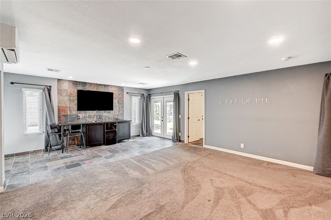 4153 Woodcrest Road Las Vegas, NV 89121 - Photo 18 of 58 A dynamic media wall with stone accents anchors this spacious family room, flowing to an outdoor area through French doors.
