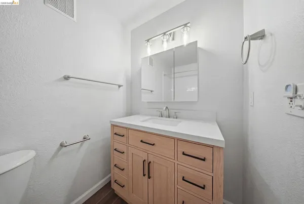 a bathroom with a granite countertop sink a toilet and a mirror