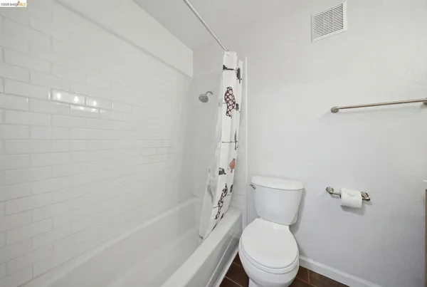 a white toilet sitting next to a bath tub and a shower