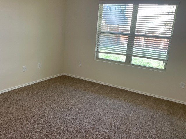 10125 Gertrudis Loop Austin, TX 78747 - Photo 6 of 27 Empty room featuring baseboards and dark carpet