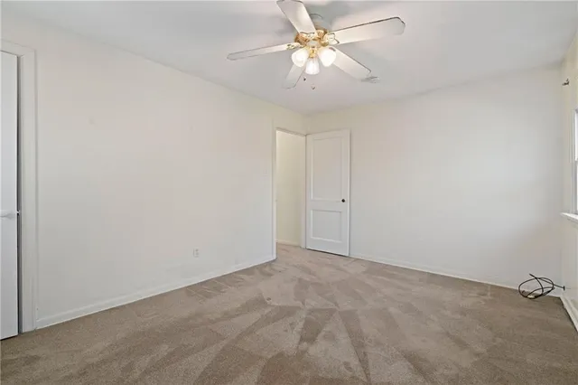 an empty room with a chandelier fan and closet area