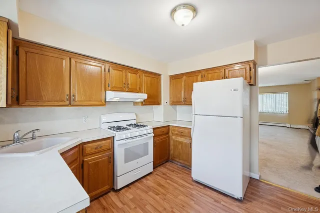 a kitchen with a refrigerator sink stove and wooden floor