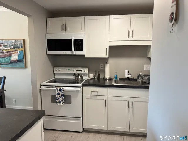 a kitchen with granite countertop white cabinets and a stove
