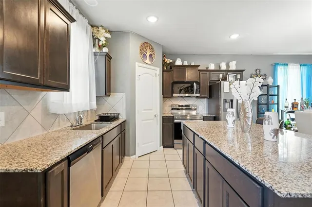 a large kitchen with stainless steel appliances a large counter top a stove a chimney a sink and dishwasher