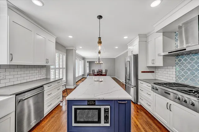 a kitchen with kitchen island stainless steel appliances a stove sink microwave and cabinets