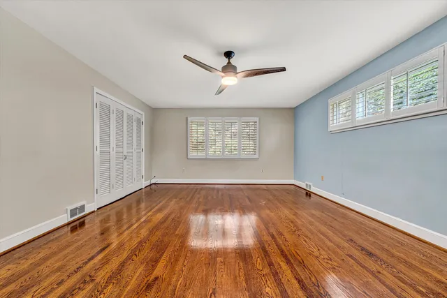 a view of empty room with wooden floor and fan