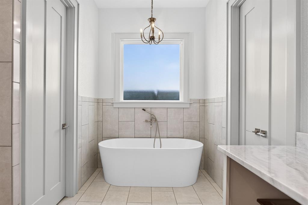 3008 Perkins Weatherford, TX 76088 - Photo 21 of 36 Freestanding soaking tub with a wall-mounted faucet, complemented by a decorative chandelier