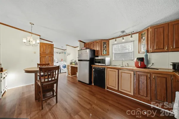 a kitchen with granite countertop wooden floors cabinets dining table and stainless steel appliances