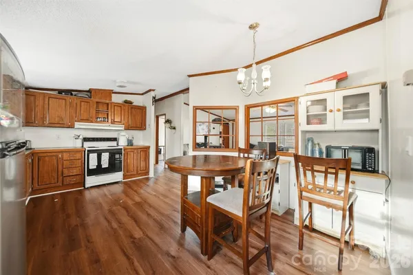 a open kitchen with stainless steel appliances granite countertop a stove top oven a dining table and chairs with wooden floor
